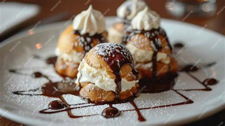 Profiteroles and vanilla ice cream on a plate.